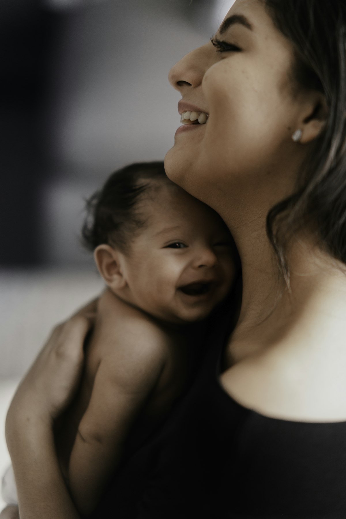 Erleichterte, lächelnde Mutter mit ihrem fröhlichen Baby im Arm